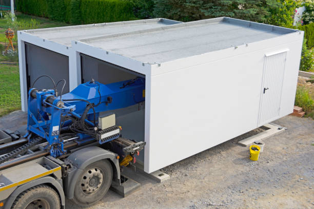 The second half of a modern prefabricated garage is placed on the strip foundation