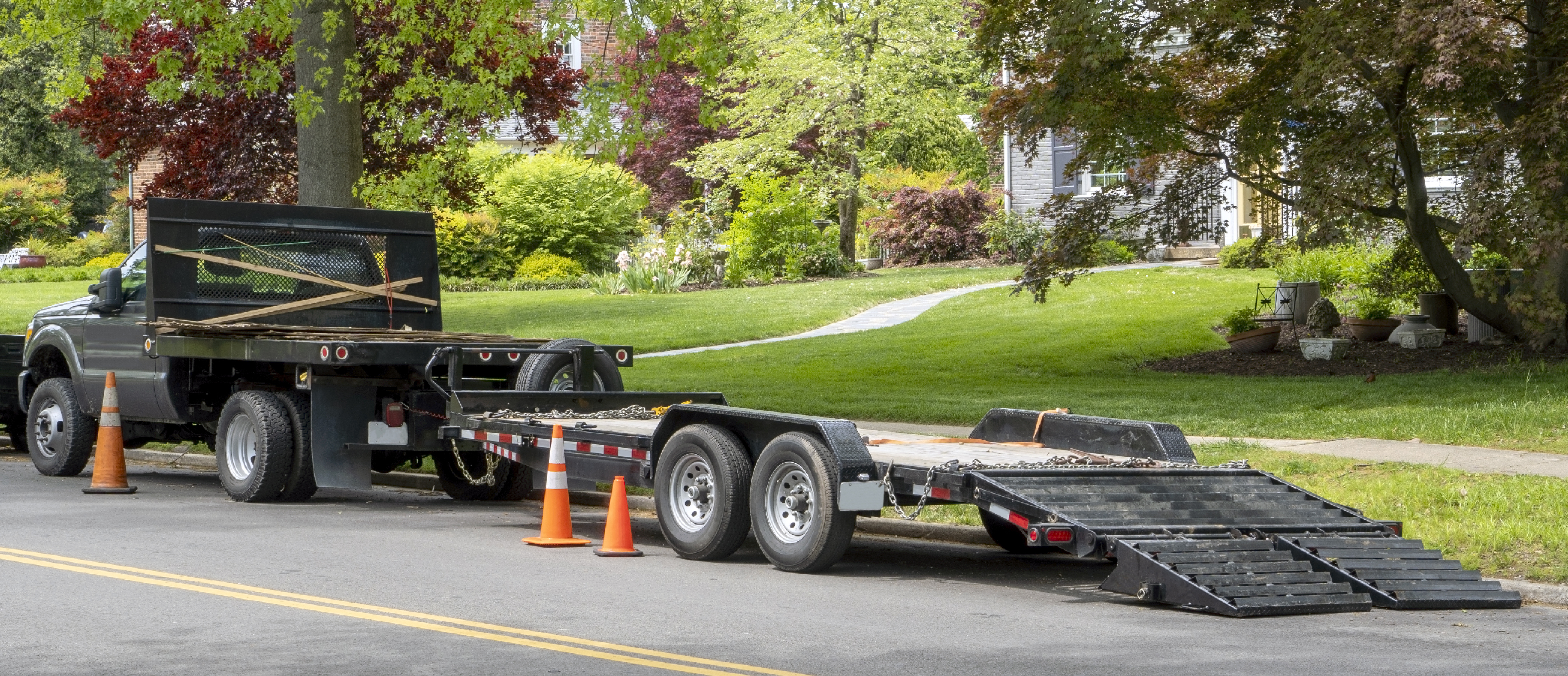 A flatbed trailer with loading ramps and safety cones, prepared for loading heavy equipment, showcasing safe loading practices.