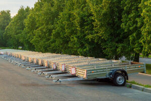 Flatbed trailers lined up in a parking lot with a lush green background, showcasing options for choosing the right trailer for hauling needs.