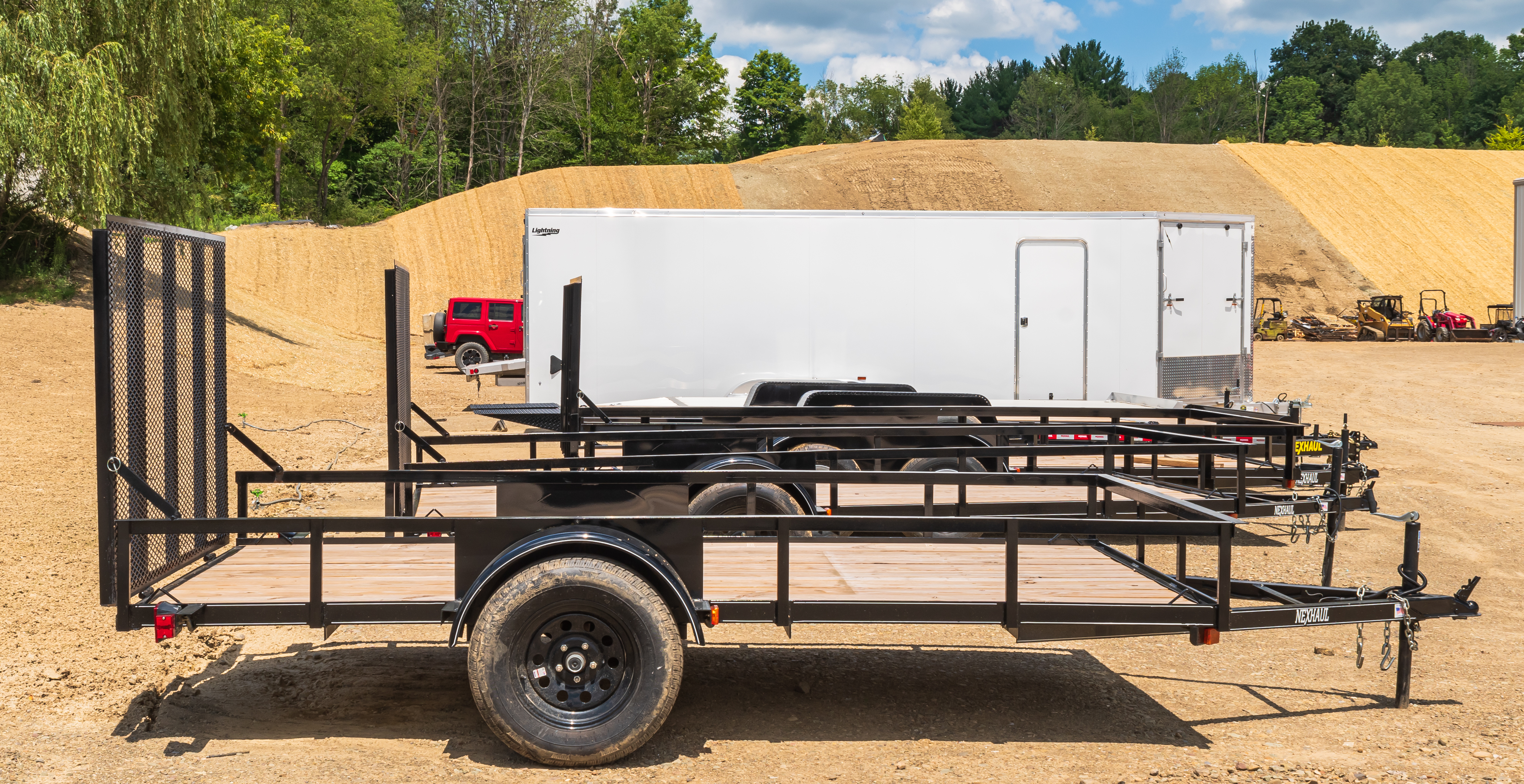 Utility trailers lined up at a construction site, showcasing options for hauling smaller equipment, landscaping tools, or recreational gear.